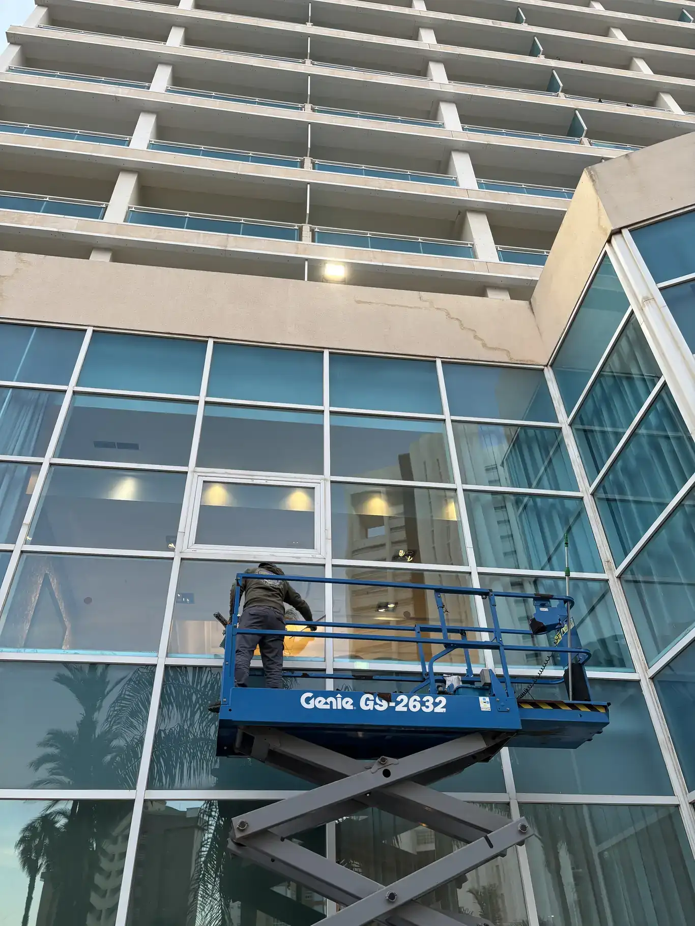 Operario en plataforma elevadora realizando limpieza de cristales en fachada de hotel en Benidorm