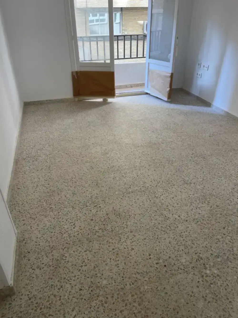 Suelo de mármol deteriorado con arañazos, manchas de obra y desgaste antes del pulido profesional