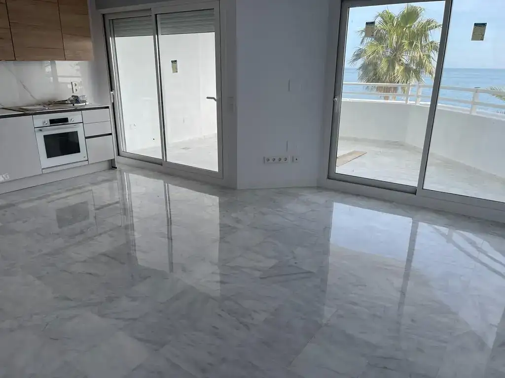 Suelo de mármol blanco recién pulido y abrillantado en un apartamento de lujo con vistas al Mediterráneo.